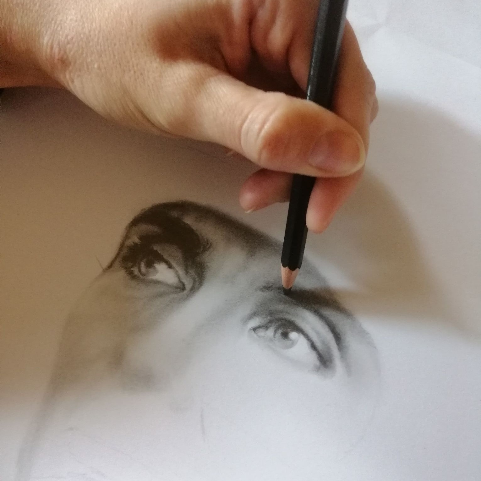 Hånd med blyant som tegner et ansikt.