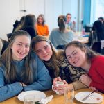 Tre smilende jenter i matsalen på Vefsn Folkehøgskole Toppen