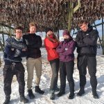 Fem elever fra Vefsn Folkehøgskole Toppen står under et gjell med fisk i Lofoten