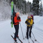 To elever fra Vefsn Folkehøgskole Toppen står klare til skitur med sekk på ryggen. Snøkledd skog i bakgrunnen.
