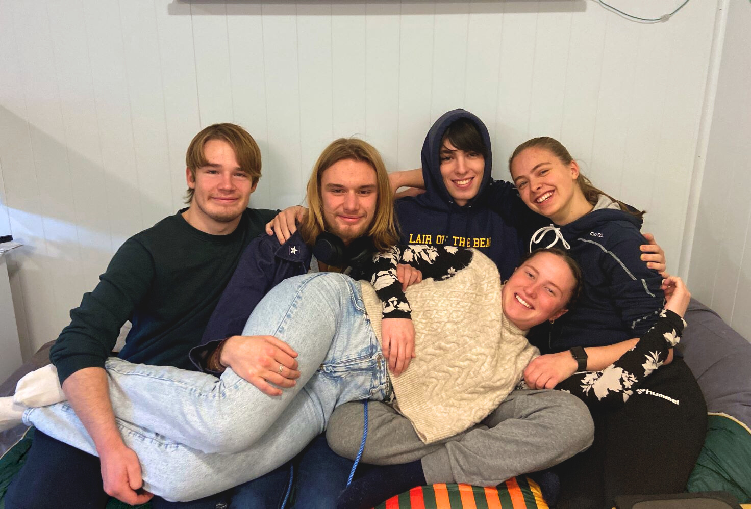 Fem elever i ei seng på internatet på Vefsn Folkehøgskole Toppen. En av dem ligger foran i fanget på de andre.
