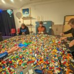 Elever fra Vefsn Folkehøgskole Toppen sitter rundt et stort bord fylt med Lego og bygger.