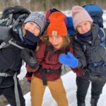 Tre elever fra Vefsn Folkehøgskole Toppen på tur i Børgefjell. Tursekk på ryggen, lue og vinterklær. Smiler og tøyser mot fotografen.