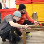 To personer monterer en benk inne på sløyden på Vefsn Folkehøgskole Toppen.