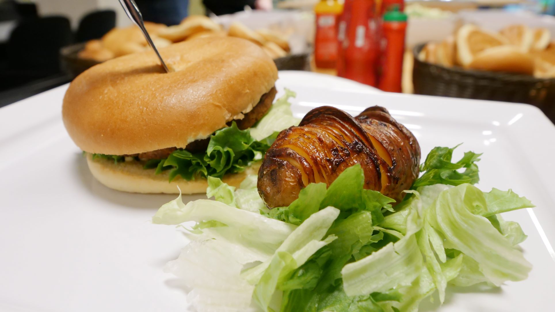 Tallerken med hjemmelaget hamburger, salat og hasselbackpoteter.