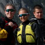 Tre elever fra Vefsn Folkehøgskole Toppen poserer for fotografen i padleutstyr.