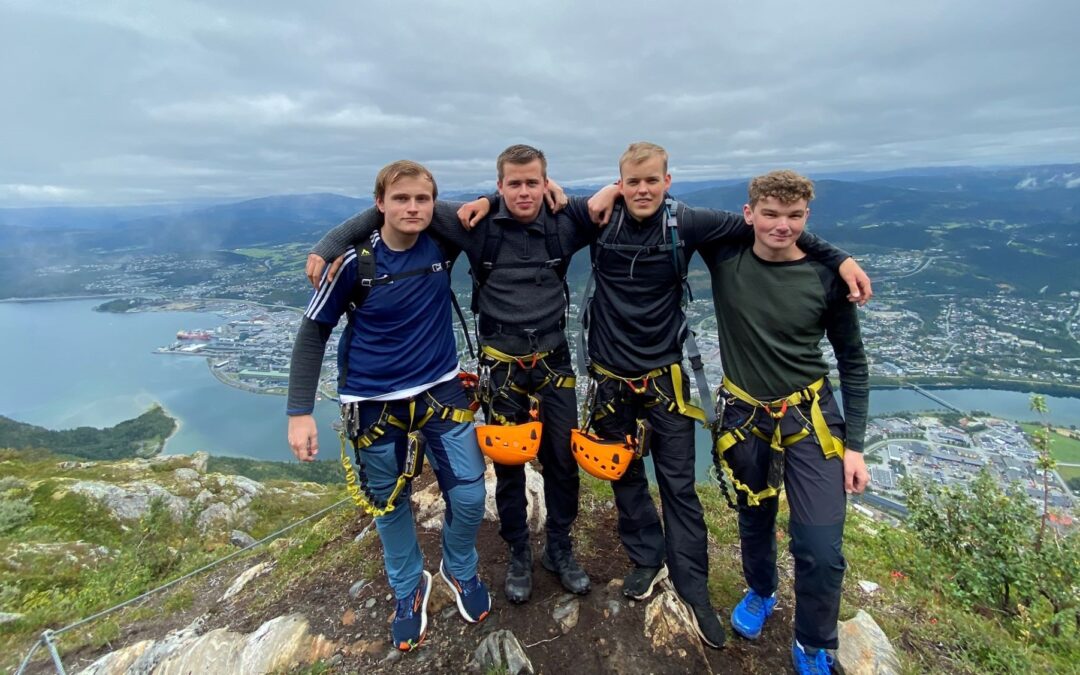 Fire elever fra VefsnFolkehøgskole Toppen står oppe på Øyfjellet. I bakgrunnen Mosjøen. Klatreseler og hjelmer i beltet.